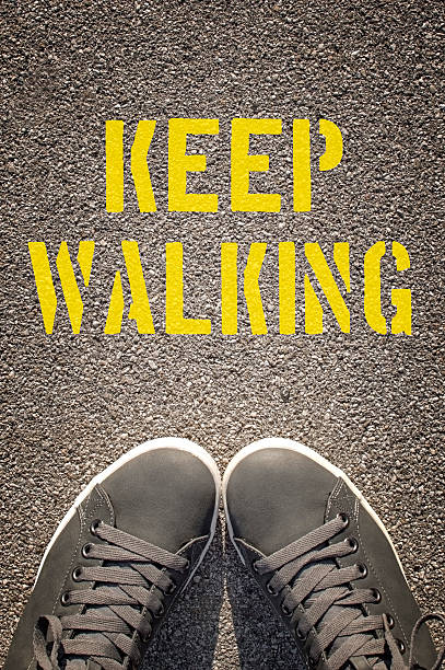 istock Sneakers with Keep Walking written on the asphalt road 492217490