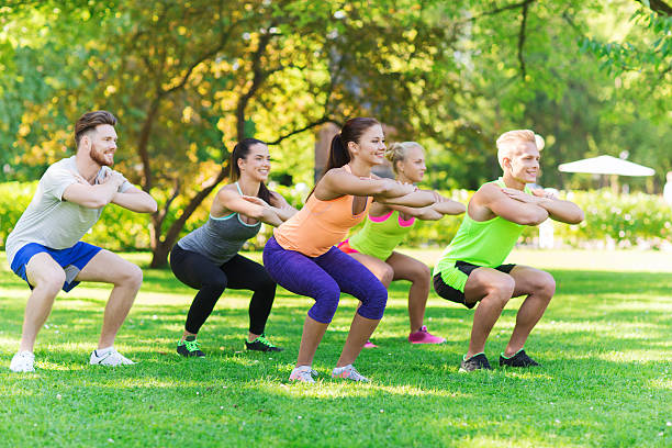 group of friends or sportsmen exercising outdoors fitness, sport, friendship and healthy lifestyle concept - group of happy teenage friends or sportsmen exercising and doing squats at boot camp fitness boot camp stock pictures, royalty-free photos & images