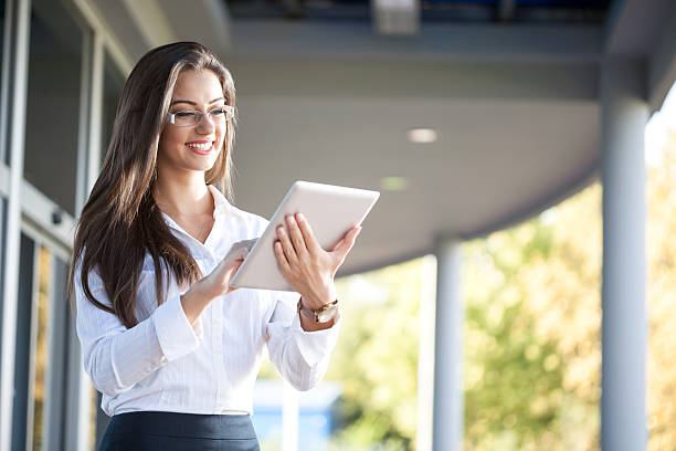 istock Smiling businesswoman using electronic tablet outside 492225648