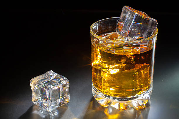 istock Glass of whiskey with ice on a dark background 492225832