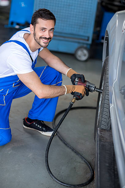 istock smiling mechanic repairing car wheel 492249440