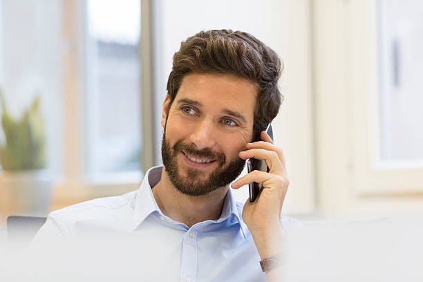 istock Handsome bearded man on the mobile phone in office 492253422