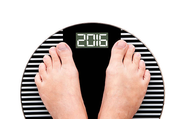 istock 2016, feet on a weight scale isolated on white background 492256006