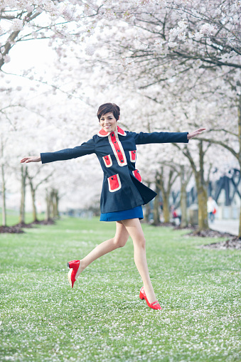 Series of a cute girl with pixie haircut, wearing retro dresses, standing on the water front of Portland, Oregon with Cherry Blossoms blooming everywhere.