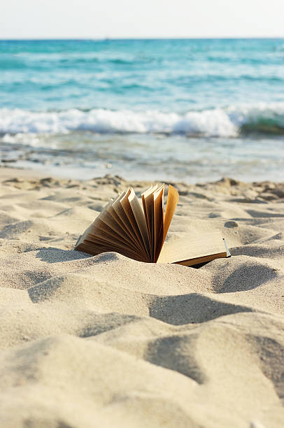 открытая книга лягте на песчаном пляже. - beach sand стоковые фото и изображения