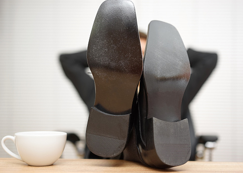 Relaxed businessman is sitting in office with feet on the desk