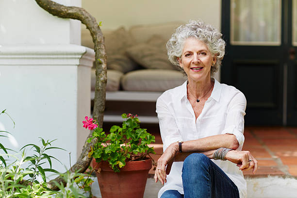 confident senior woman sitting at porch - shirt white women blouse stock-fotos und bilder