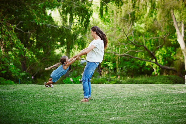 mother and daughter playing in park - child swing swinging playing стоковые фото и изображения