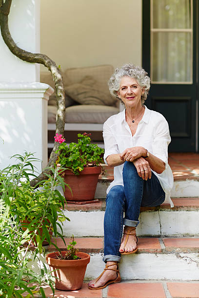 Contented senior woman sitting at porch Full length portrait of contented senior woman sitting at porch grey hair on floor stock pictures, royalty-free photos & images