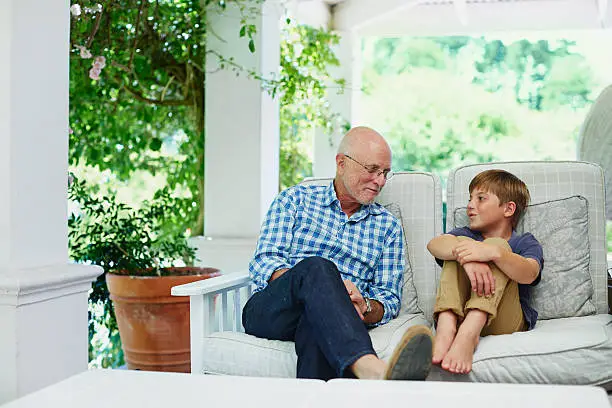 Photo of Boy communicating with grandfather at porch