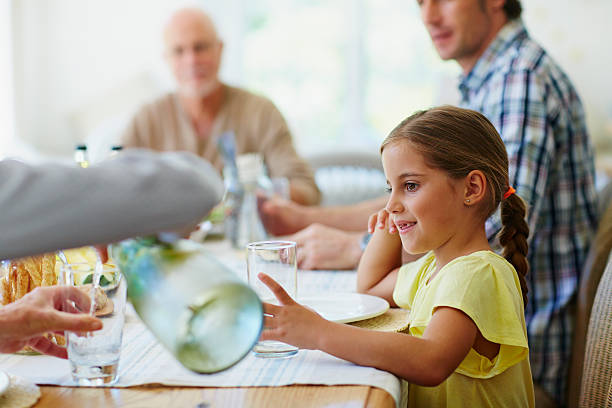 girl looking at mother pouring water in glass - south africa waist up indoors image technique 뉴스 사진 이미지