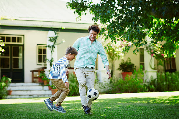 father and son playing soccer in lawn - people caucasian sport family fotografías e imágenes de stock