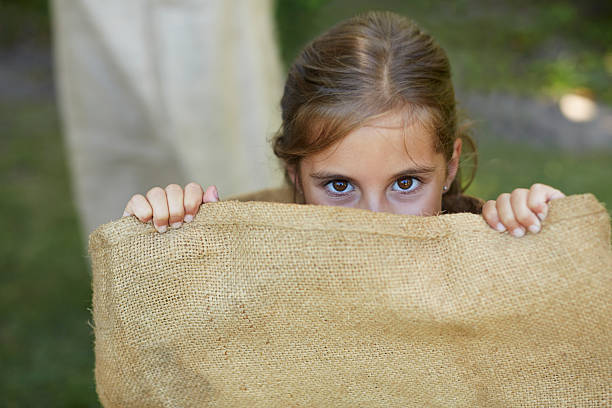 girl hiding in sack - child playing sack race sports race - fotografias e filmes do acervo