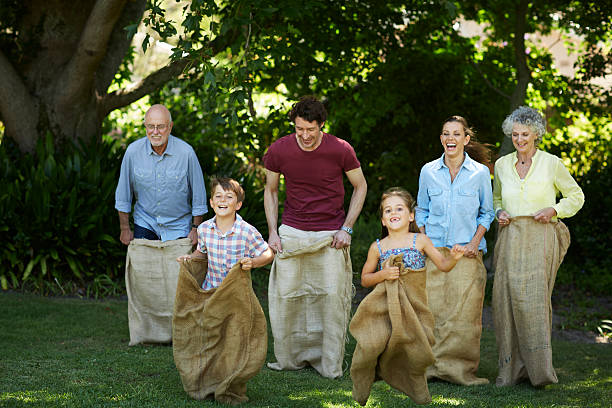 family having sack race in park - burlap sack zdjęcia i obrazy z banku zdjęć