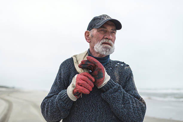 istock Senior beachcomber with work gloves on the beach holding sack. 492277258