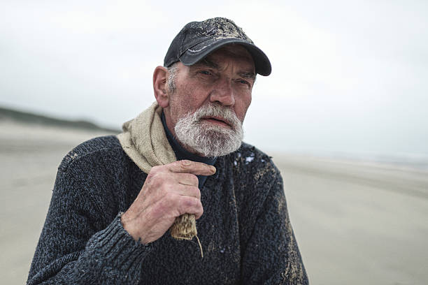 istock Pensive senior beachcomber with baseball cap holding burlap sack 492277344