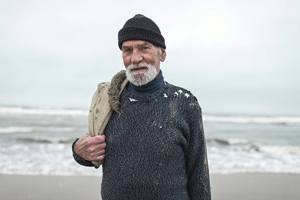 Smiling beachcomber with burlap sack and woolen cap near sea.