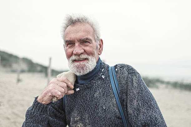 "beachcomber sênior na praia. " com tecido de saco. - torned - fotografias e filmes do acervo