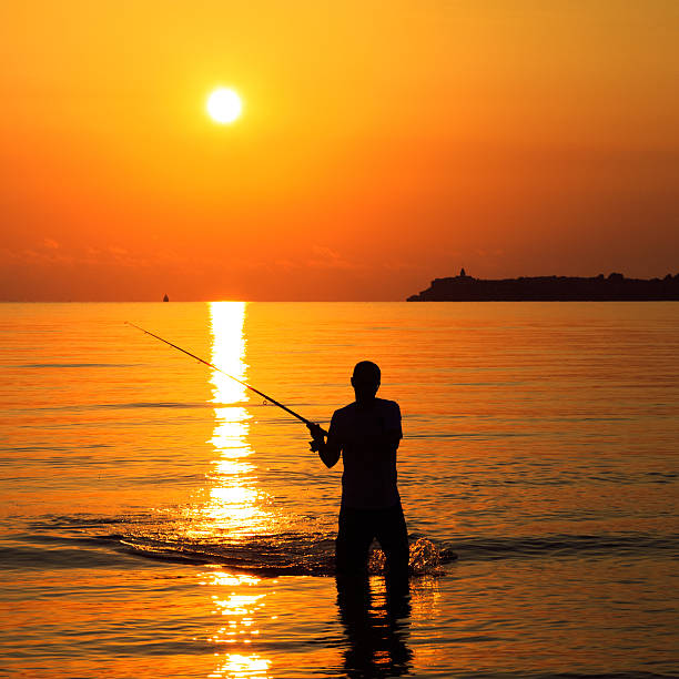Fisherman silhouette at sunrise near the sea