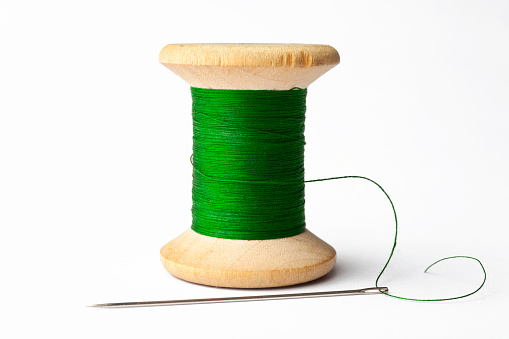 Sewing layout with multicolored spools of thread close-up, needles, electric sewing machine. Filling the thread into the sewing needle, adjusting the tension. hobby, home business
