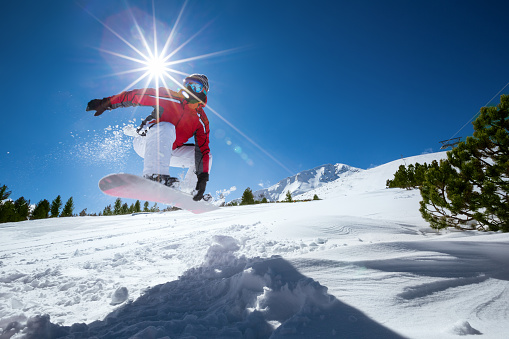 Snowboarder taking a jump in fresh snow.