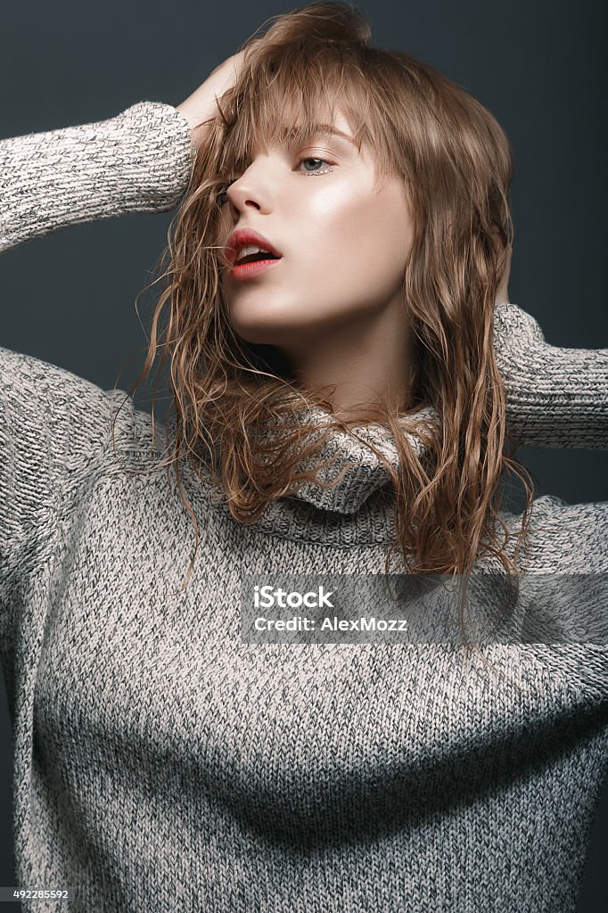 Portrait of a young girl in sweater studio Portrait of a young girl in a sweater the studio with nude makeup mua on dark gray background 2015 Stock Photo