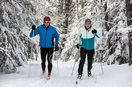 A man and woman cross country skiing on a groomed ski trail in the Midwest United States.