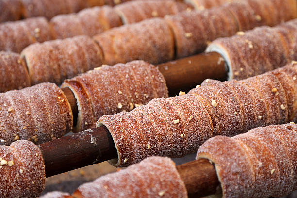 Prague stick bread Trdelník is a traditional Slovak/Czech sweet pastry. It is made from rolled dough that is wrapped around a stick, then grilled and topped with sugar, cinnamon and/or walnut mix. trdelník stock pictures, royalty-free photos & images
