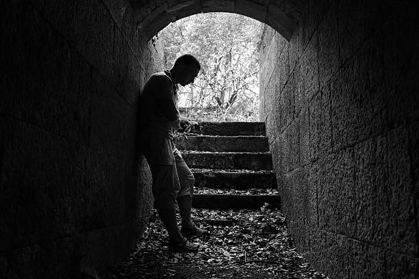 istock Young sad man stands in dark stone tunnel 492311476