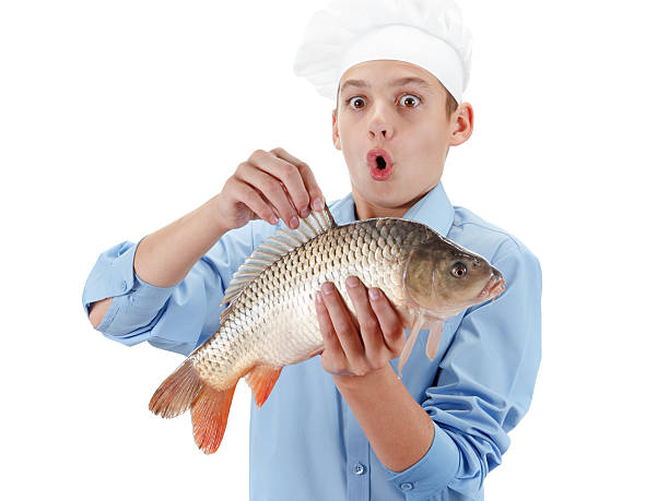 istock Young chef holding a fish carp on white background 492314438