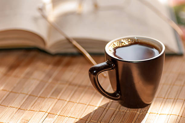 istock cup of coffee, standing next to an open book 492317304