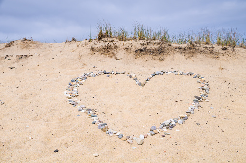 A heart shape is designed on a Provincetown sand dune using small stones polished smooth by relentles waves.