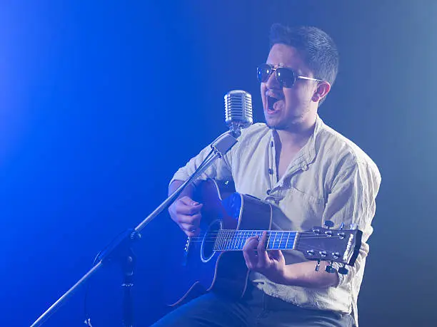 Photo of Portrait of a young singer playing acoustic guitar in smoke