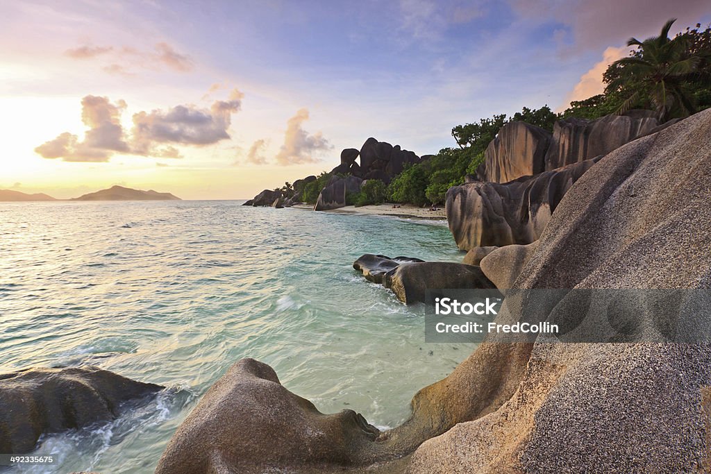 Dramatic sunset over La Digue island in Seychelles Picture taken at sunset on La Digue island, in Seychelles. The beach depicted is Anse Source d'Argent which is seen as one of the most beautiful beach in the world (as per National Geographic). It's typical for its granite boulders on the beach and its turquoise water. Anse Source d'Argent Stock Photo