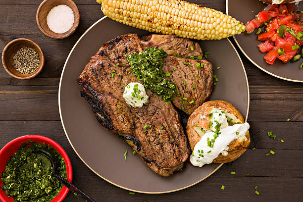 Steak Dinner An overhead close up shot of a grilled porterhouse steak and all the trimmings. baked potato sour cream stock pictures, royalty-free photos & images