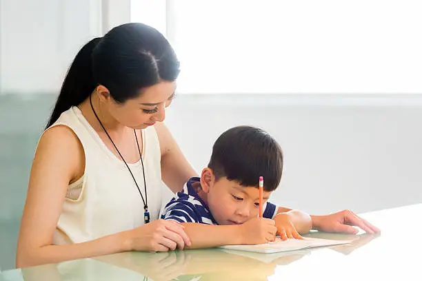 A Chinese woman and a little boy work on schoolwork.