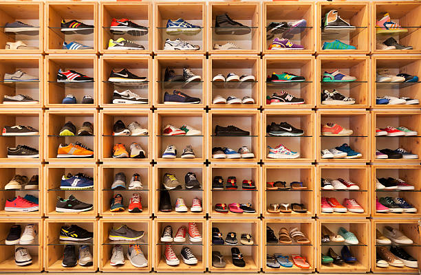 Different shoes displayed in a shoe shop. Playa Del Ingles, Spain - May 16, 2014: Different shoes exhibited in a shoe shop in the Yumbo shopping center. Visible brands are Lacoste, Nike, Adidas, Asics, New Balance, Diesel and DKNY. shoe store stock pictures, royalty-free photos & images