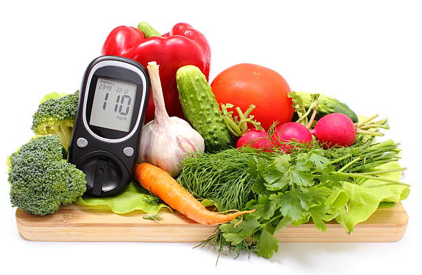 Glucometer and fresh vegetables on wooden cutting board stock photo