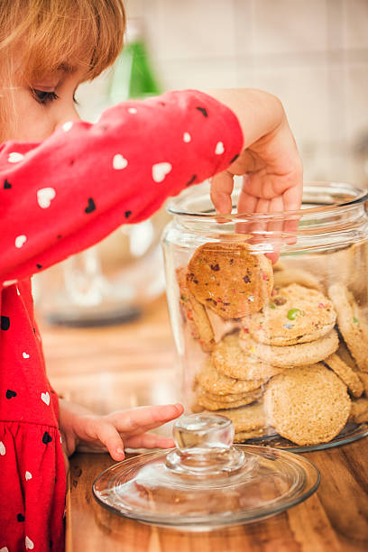 istock Cute Little Girl Taking Chocolate Chip Cookie From Jar 492361458