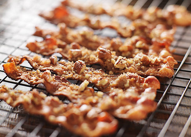 candied bacon with pecans and brown sugar candied bacon with pecans and brown sugar cooling on baking rack candied fruit stock pictures, royalty-free photos & images