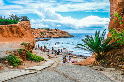 Cala de Sant Vincent, Spain - August 18, 2015: Beach in Ibiza featuring people enjoying the sun during the day.