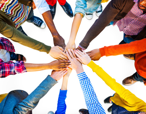 Group of business persons standing in a circle and stacking hands