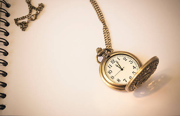 istock shadow and pocket watch on a old book,Vintage 492369654