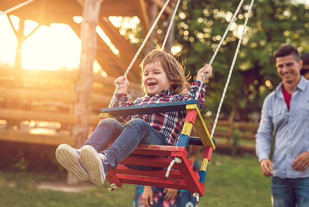 alegre niño pequeño balanceo en la puesta de sol. - child swing swinging spring fotografías e imágenes de stock