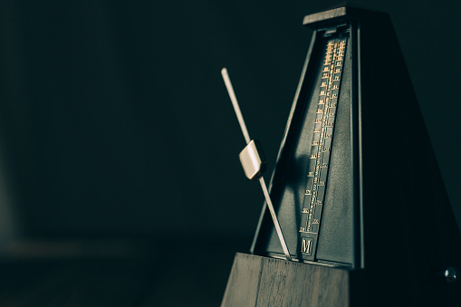 Color shot of a vintage metronome, on a black background.