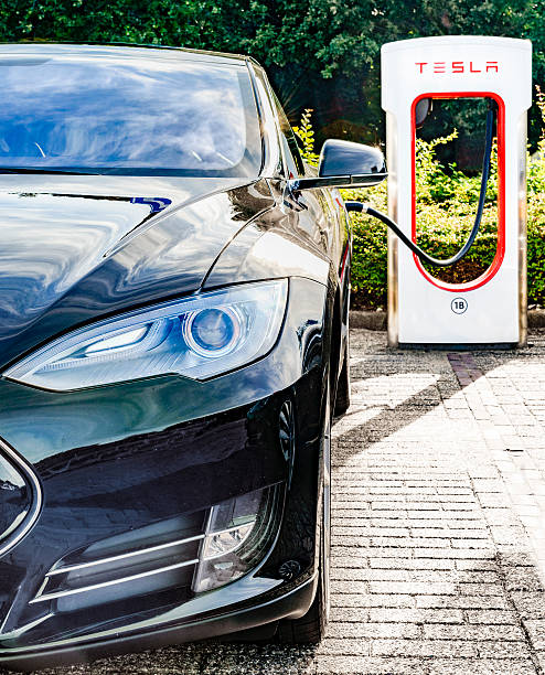 tesla modelo do carro elétrico em uma estação de carga supercharger - tesla - fotografias e filmes do acervo