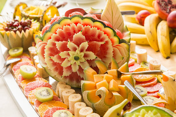 Fruit Art and Food Garnishing Fresh sliced multi-colored fruit carvings on buffet table. fruit carving stock pictures, royalty-free photos & images