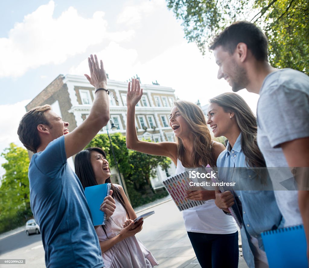 Students giving a high-five Excited group of students giving a high-five and looking very happy Educational Exam Stock Photo