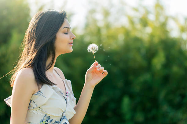 istock Young woman blowing a dandelion 492404201