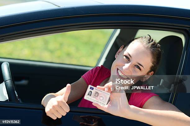 Alegre Joven Feliz En Coche Mujer Mostrando Nueva Licencia De Conducir Foto de stock y más banco de imágenes de Carné de conducir